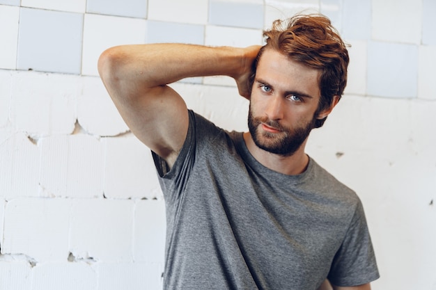 Close up Portrait of a young bearded man standing against grunge weathered wall