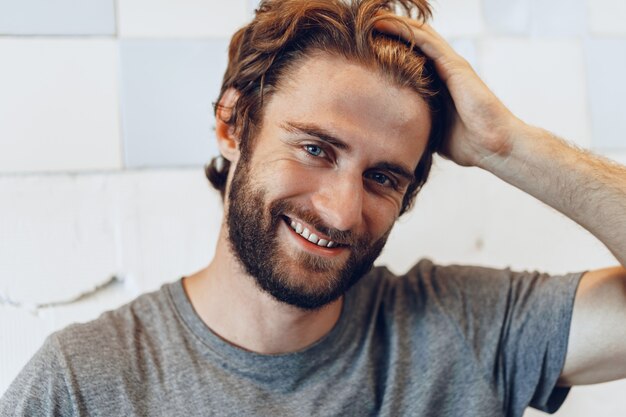 Close up Portrait of a young bearded man standing against grunge weathered wall