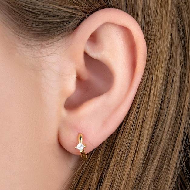 Close up portrait of young beautiful brunette female model presenting golden and silver earrings and ring Side view of woman in formal suit posing in studio isolated on white background