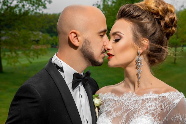 Close up portrait of young beautiful married couple kisses outdoors