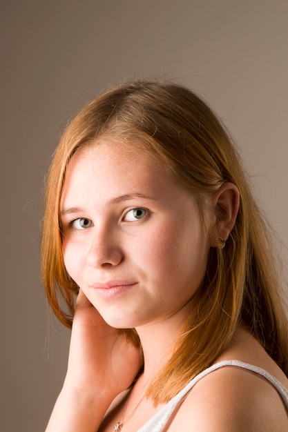 Close-up portrait of a young beautiful red-haired girl smiling while looking at the camera.