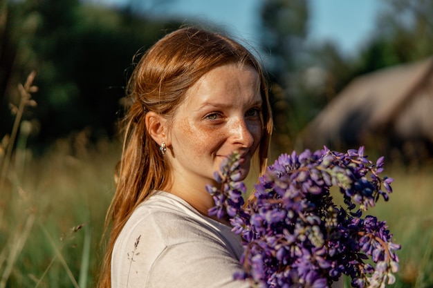 Close up portrait of young beautiful redhead woman with freckles wearing white dress posing in the nature Girl with red hair holding flowers Natural beauty Diversity individual uniqueness