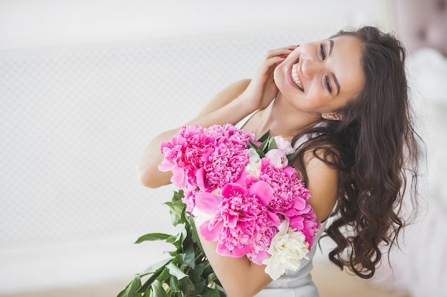 屋内の花を持つ若い美しい女性の肖像画をクローズアップ