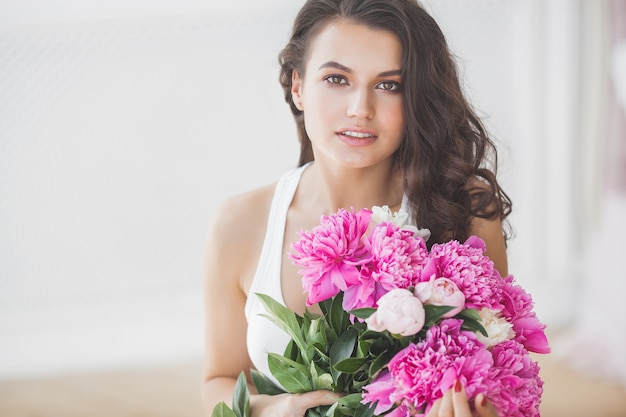 屋内の花と若い美しい女性の肖像画をクローズアップ
