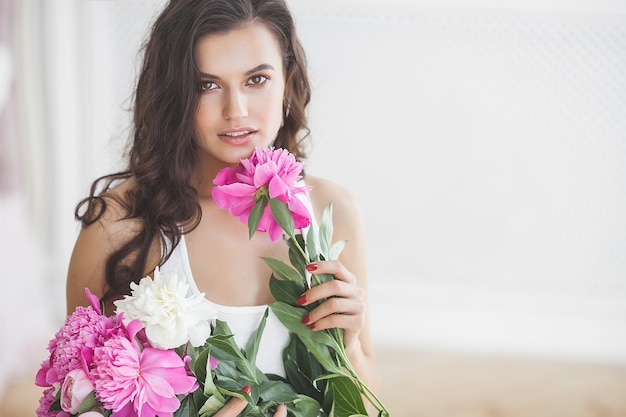 屋内の花と若い美しい女性の肖像画をクローズアップ