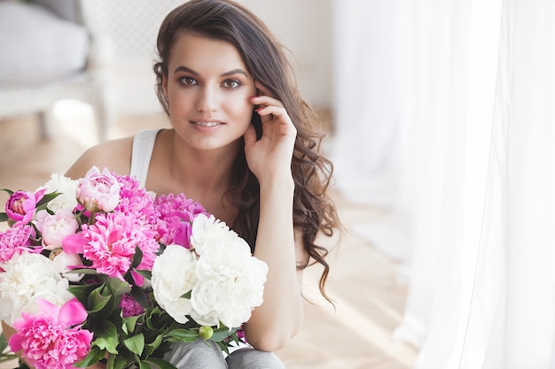 屋内の花を持つ若い美しい女性の肖像画をクローズアップ