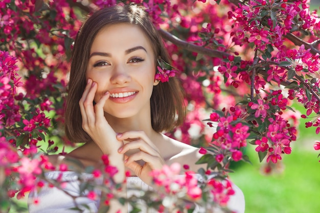 Close up portrait of young beautiful woman with perfect smooth skin. Attractive lady in flowers. Facial portrait of beautiful female.