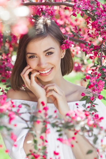 Close up portrait of young beautiful woman with perfect smooth skin. Attractive lady in flowers. Facial portrait of beautiful female.