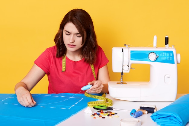 Close up portrait of young brunette seamstress working with her pattern