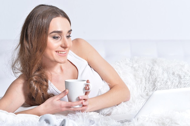 Close up portrait of young brunette woman relaxing in bed