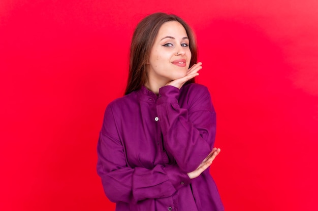 Close up portrait of young cheerful isolated on red studio background in purple shirt smiling