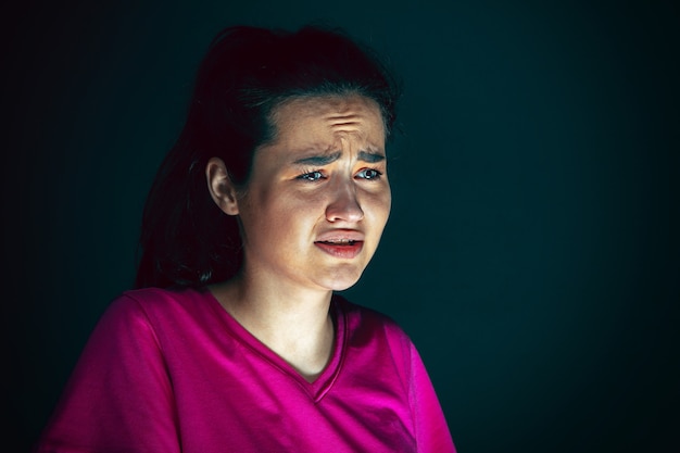 Close up portrait of young crazy scared and shocked woman isolated on dark background