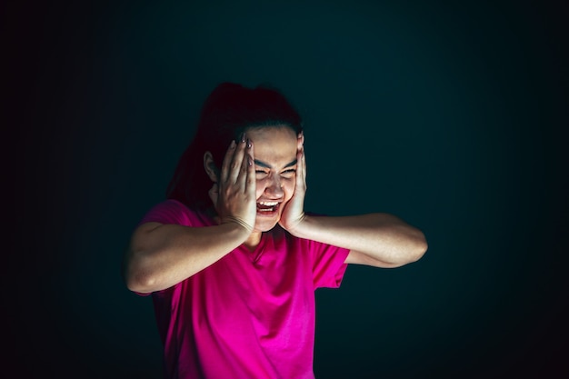 Close up portrait of young crazy scared and shocked woman isolated on dark background