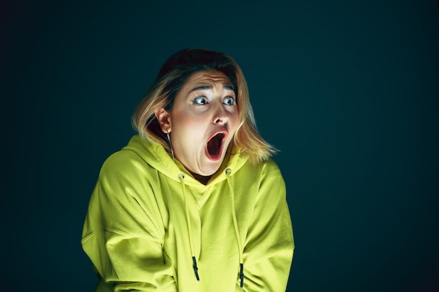 Close up portrait of young crazy scared and shocked woman isolated on dark background