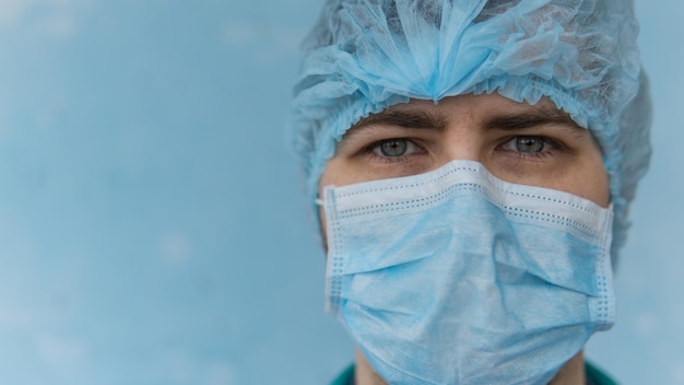 Close up portrait of young doctor in medical mask looking at camera