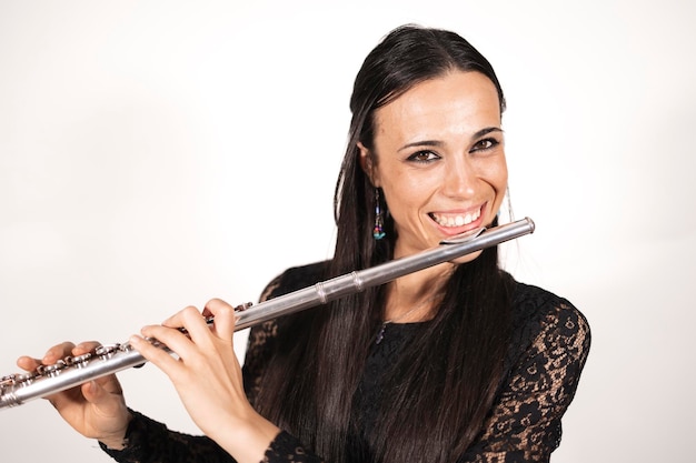 Close up portrait of a young elegant female flutist smiling with joy