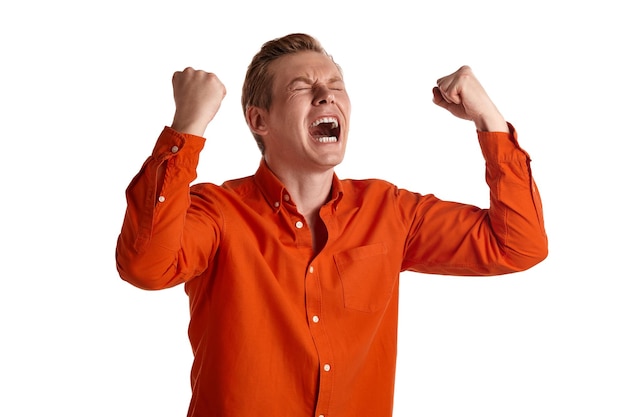 Close-up portrait of a young excited ginger peson in a stylish orange shirt acting like he is overjoyed about something while posing isolated on white studio background. Human facial expressions. Sinc