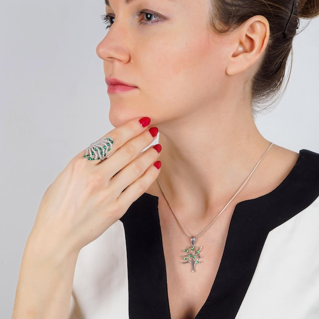 Close up portrait of young female model presenting silver ring Crop of woman with perfect makeup posing in studio isolated on light gray