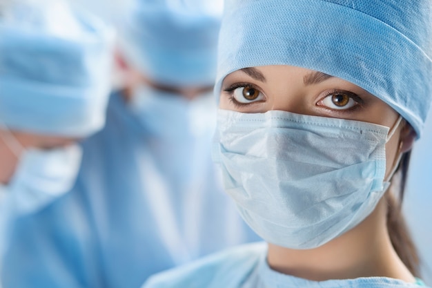 Close up portrait of young female surgeon doctor surrounded by her team