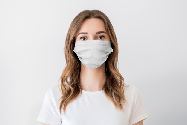 Close up portrait of a young girl wearing protective medical face mask isolated on a white background