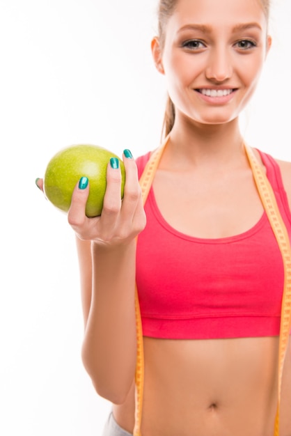 Close-up portrait of young girl with apple and measuring tape