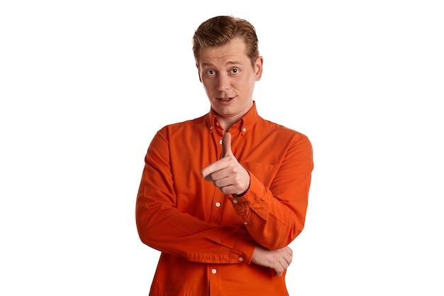 Close-up portrait of a young good-looking ginger male in a stylish orange shirt gesticulating and looking at the camera while posing isolated on white studio background. Human facial expressions. Sinc