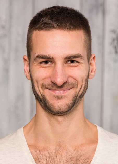 Photo close-up portrait of young handsome man posing in studio for photographer. man in white t-shirt smiling for the camera.