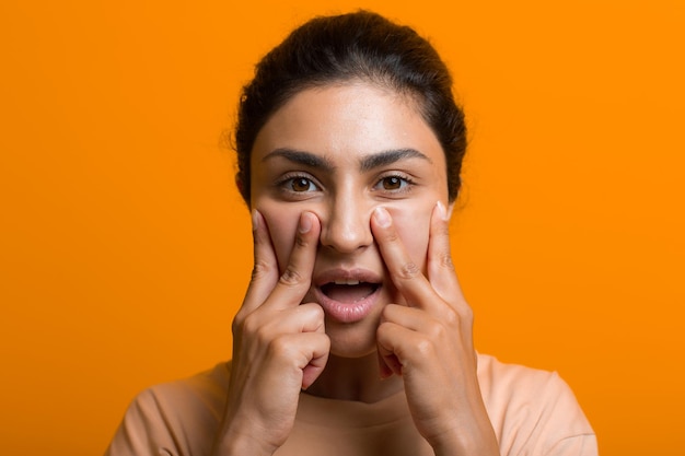 Close up portrait of young indian american woman doing facebuilding yoga face gymnastics yoga self massage