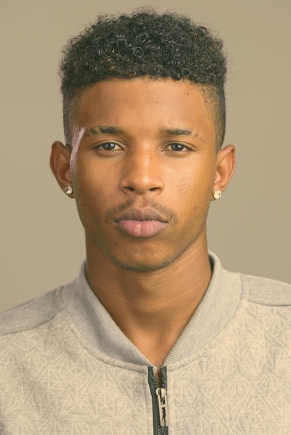 Close-up portrait of young man against gray background