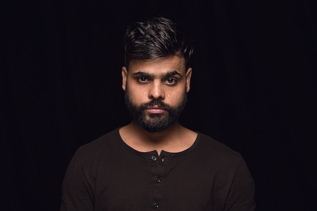 Close up portrait of young man isolated on black  wall.  real emotions of male model. Crying, sad, dreary and hopeless. Facial expression, human emotions concept.