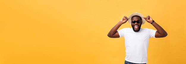 Close up portrait of a young man laughing with hands holding hat isolate over yellow background person