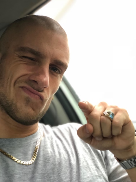 Close-up portrait of young man pointing while sitting in car