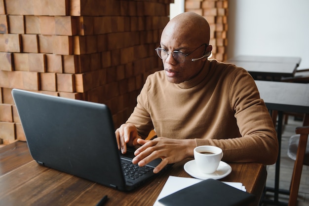 Close up portrait of young man sitting in cafe working on laptop computer