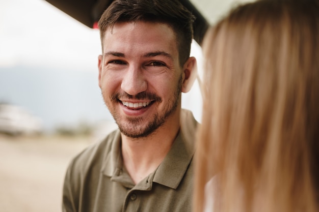 Close up portrait of a young man standing near car in contryside