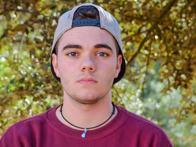 Photo close-up portrait of young man wearing cap against trees