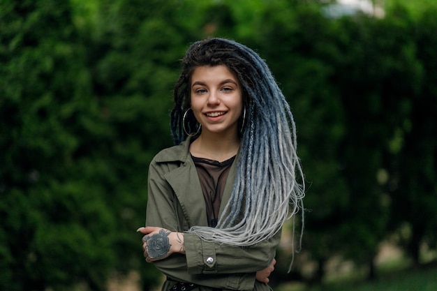 Close up portrait of a young pretty smiling woman with dreadlocks, cheerfully looking at the camera walking in city