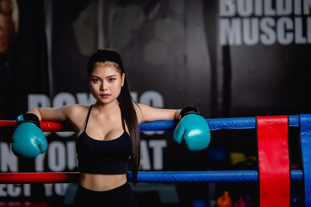 Close up portrait young pretty woman in boxing glove standing on canvas after training with tired, workout in fitness gym,    