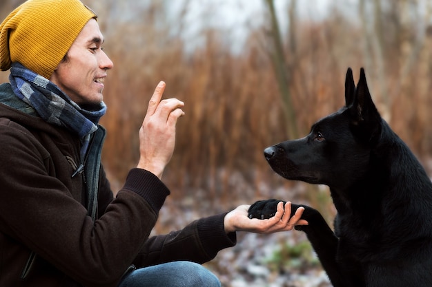 Close up portrait of a young stylish caucasian man training with big black dog in outdoor
