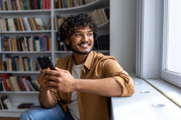 Close up portrait of young successful hispanic student man with curly hair looking out window