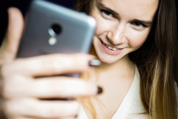 Крупным планом портрет молодого успешного студента, делающего селфи фото. Женщина, читающая хорошие новости в мобильном телефоне. Положительные эмоции людей. Концепция коммуникации.