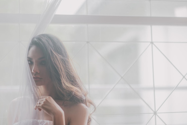 Photo 家の窓のカーテンの近くの若い女性のクローズアップ肖像画