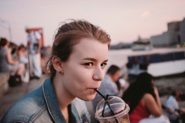 close-up portrait of young woman drinking outdoors