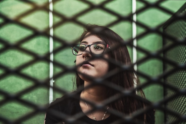 Photo close-up portrait of young woman behind fence