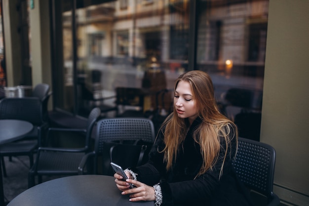 スマートフォンを手に持つ若い女性フリーランサーのポートレートを閉じます