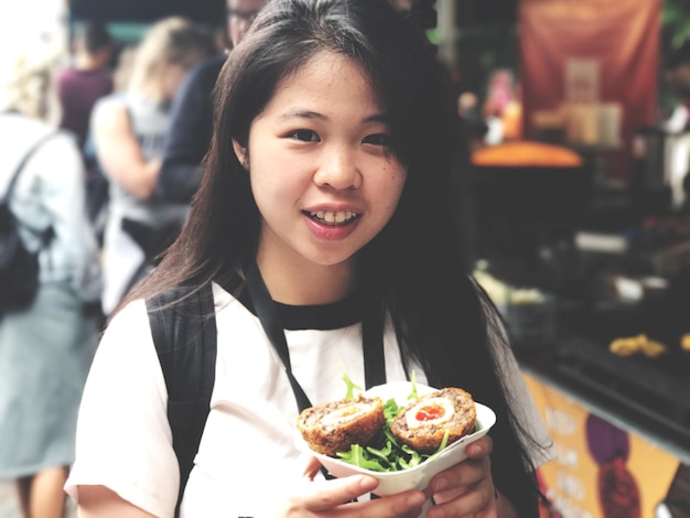 ストリートフードを食べている若い女性のクローズアップ肖像画
