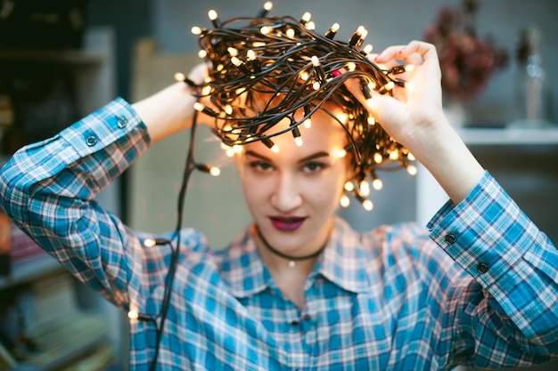 Foto ritratto ravvicinato di una giovane donna che tiene in mano delle luci luminose a casa