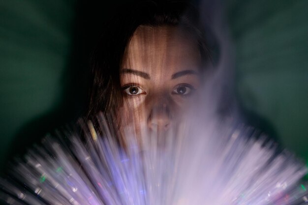 Photo close-up portrait of young woman holding multi colored fiber optic