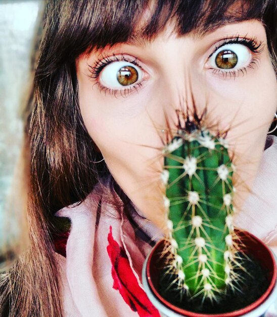 Photo close-up portrait of young woman kissing cactus