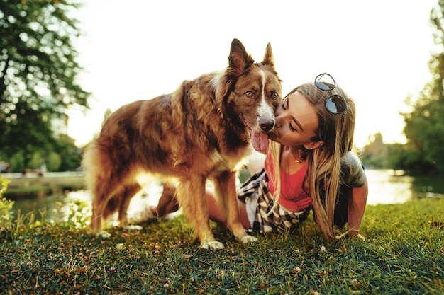 Close up portrait of young woman kissing her dog in the park