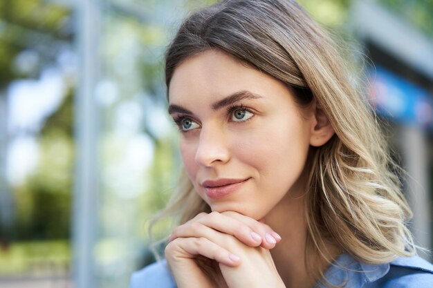 座って考えて手に希望に満ちた笑顔の無駄のない頭を探している若い女性の肖像画を間近します。